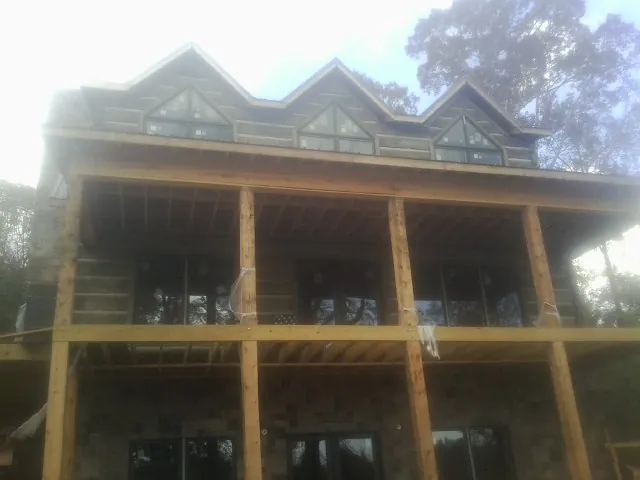 Dormers and porch framing on a large log home under construction — Roof Coating work by our crew in Aragon