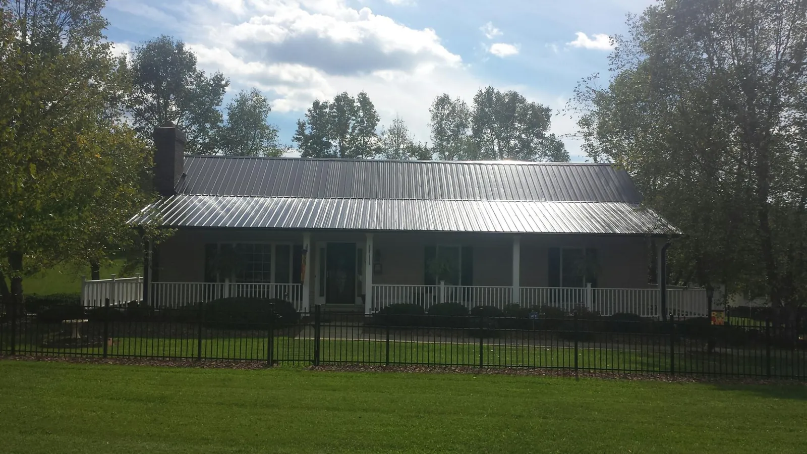 Gray metal roof on a brick ranch with a full width front porch — Gutter Guard Installation work by our crew in Aragon