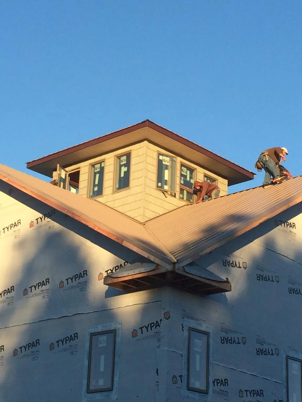 Roofers working around a rooftop cupola on a new metal roof at sunset — Roof Waterproofing in Aragon by Roofing Brothers